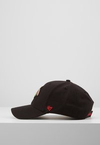 Black baseball cap with colorful embroidered patches on the front, a curved brim, and red 47 logo on the side. Soft fabric texture.