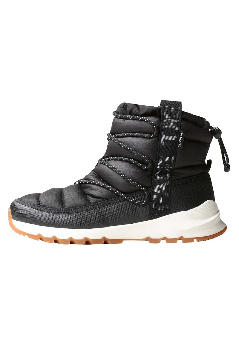 Botte d'hiver isolée noire avec lacets à motif, semelle épaisse blanche, et logo "The North Face" sur la bride latérale avec languette à l'arrière.