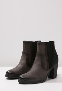 Stivaletti alla caviglia in pelle nera con tacco spesso, pannelli laterali elastici e pannello posteriore testurizzato. Finitura liscia con dettagli cuciti.