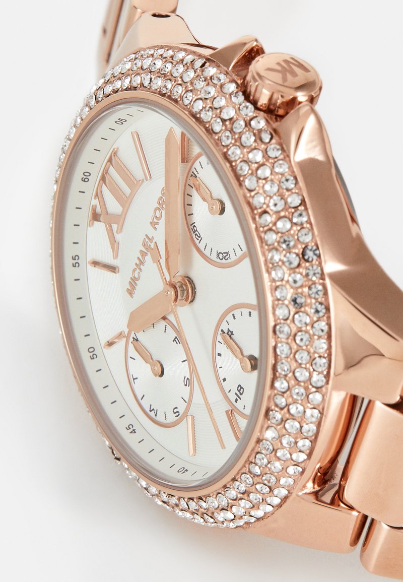 Roségoldene Chronograph-Uhr mit weißem Zifferblatt, mit Kristallen verziertem Gehäuse, drei Unterzifferblättern und einem Gliederarmband. Römische Zahlen an 12 und 6.
