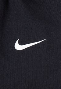 Czarna tkanina o gładkiej fakturze z wyraźnym białym logo Nike Swoosh. Projekt jest prosty i sportowy, skupiający się na marce.