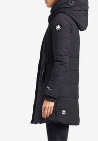 Svart kviltad lång jacka med huva, med en rund logotyp på höger ärm och en label på vänster, tillverkad av texturerad clen.