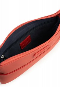 Borsetta rettangolare arancione con un esterno texturizzato, dotata di un interno nero e una chiusura con zip. Include un piccolo etichetta rossa all'interno.