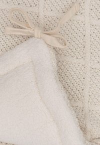 Beige gebreide deken met een geglazuurde patroon, voorzien van een zachte witte fleece achterkant en een crèmekleurige ribbond als accent.