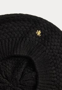 Melna adīta cepure ar kabeli adījuma rakstu, ar ribotu apkakli un mazu zelta "RL" logo akcentu. Mīksta tekstūra visā cepures virsmā.