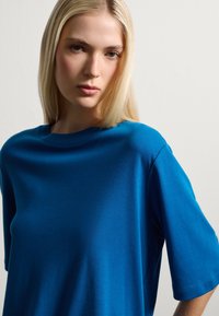 Camiseta de algodón azul con corte relajado, escote redondo y mangas cortas. Textura suave, diseño minimalista y sin patrones o acentos visibles.