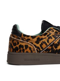 Tenis cu imprimeu leopard, având o parte superioară din blană sintetică texturată, accente din piele neagră și o talpă din cauciuc brun cu branding embossat.