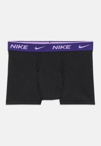 Crne bokserice s ljubičastim elastičnim pojasom na kojem se ponavlja bijeli logotip "NIKE". Glatka tkanina s prednjim otvorom za letenje.