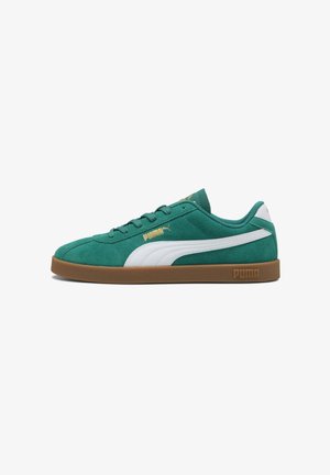 Roheline suede'i tennis paar valgetes aktsentides, tekstuurse pinnaga, kummist tallaga ning kuldsete logodega külgedel ja keeles.