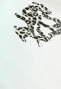 Textil blanco con un diseño audaz y abstracto de estampado de leopardo en negro y gris, con textura suave y líneas fluidas superpuestas.