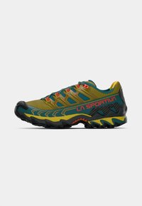 Takumis skriešanas apavi zaļā, dzeltenā un melnā krāsā ar sarkano "La Sportiva" logo un izturīgu zoli, attēloti no ārējās puses uz baltā fona.