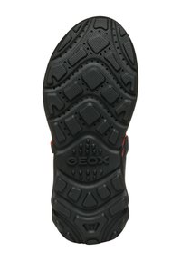 Suela de zapato de goma negra con patrones de agarre texturizados, orificios de ventilación circulares y prominente marca "GEOX". Presenta un diseño robusto y contorneado.