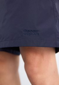 Marina shorts i slätt tyg med en broderad logotyp vid fållen, med rak skärning och rena kanter.