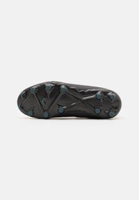 Semelle en gomme noire de chaussure de football avec une surface texturée. Présente des crampons moulés en motif radial avec des accents turquoise pour l'adhérence et la traction.