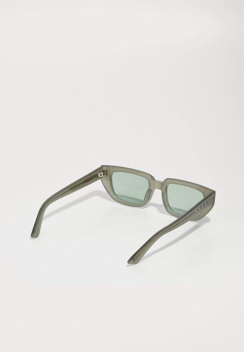 Grüngetönte Sonnenbrille mit einem semi-transparenten Rahmen, kantigem Design und geraden Bügeln. Mit einem dezenten Logo auf dem Bügel.