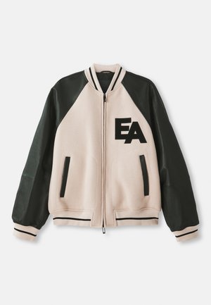 Veste varsity beige et noire avec des manches en cuir, fermeture éclair sur le devant, deux poches verticales et logo "EA" sur la poitrine gauche.