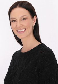 Pulover tricotat negru cu model în cablu, având un gât rotund. Modelul are părul lung și întunecat și poartă cercei rotunzi din aur.