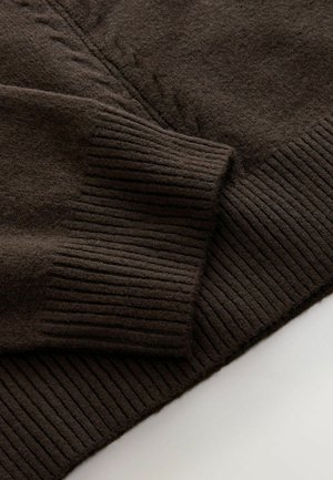 Brun strikket sweater med en glat tekstur og ribbede manchetter, samt diskrete kabelstrikdetaljer langs kroppen.
