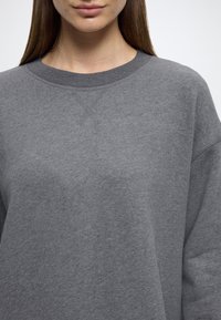 Γκρι φούτερ με στρογγυλή λαιμόκοψη, ριμπ ύφασμα στον γιακά και χαλαρή εφαρμογή. Απαλή υφή με ομαλή επιφάνεια και ελάχιστες ραφές.