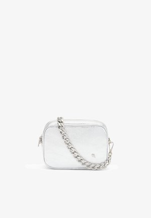 Kleine rechthoekige zilveren leren crossbodytas met ritssluiting en grove zilveren kettingband tegen een witte achtergrond.