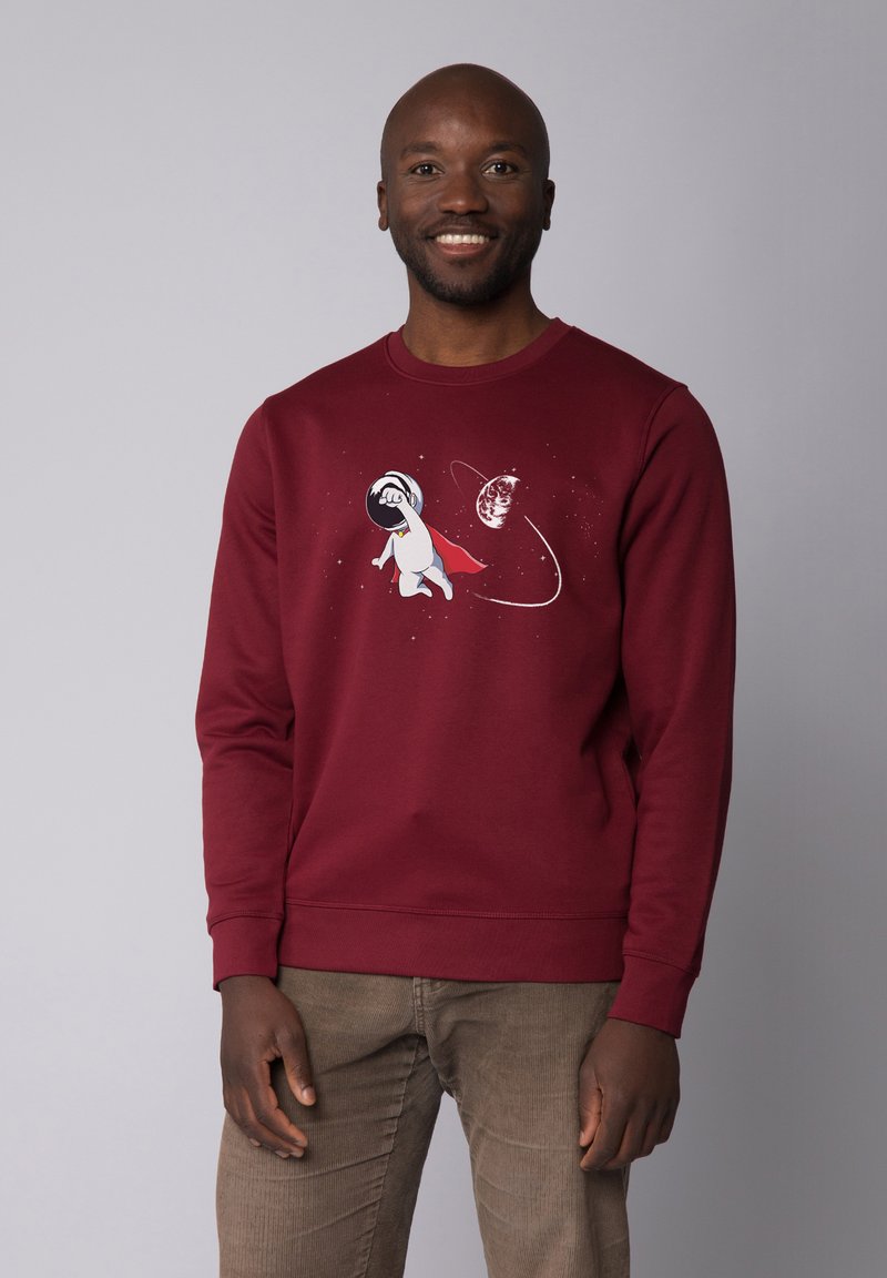 Bordeaux sweatshirt met een afbeelding van een cartoonhond in een ruimtepak, met een rode cape, omringd door sterren en een planeetontwerp.