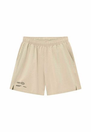 Short beige à taille élastique avec poches latérales, petit texte noir et graphisme de globe près de l'ourlet gauche.