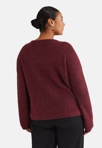 Maglione borgogna lavorato a maglia con finitura testurizzata, scollatura rotonda e spalle cadenti. Maniche lunghe, vestibilità comoda e tessuto morbido.