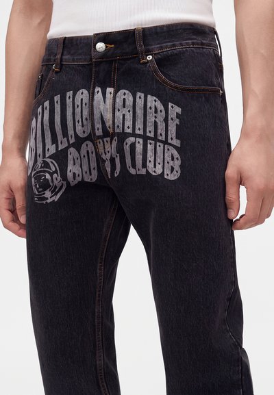 Μαύρα τζιν με μεγάλο λευκό κείμενο "Billionaire Boys Club" και λογότυπο κράνους αστροναύτη τυπωμένα στο εμπρόσθιο μέρος του μηρού.