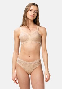 Beige pitsik, millel on pehme ja läbipaistev kangas, kuju andvad tassid ja reguleeritavad rihmad. Kokku sobivad beige pitsalised aluspüksid, millel on lainetav vöödetail.