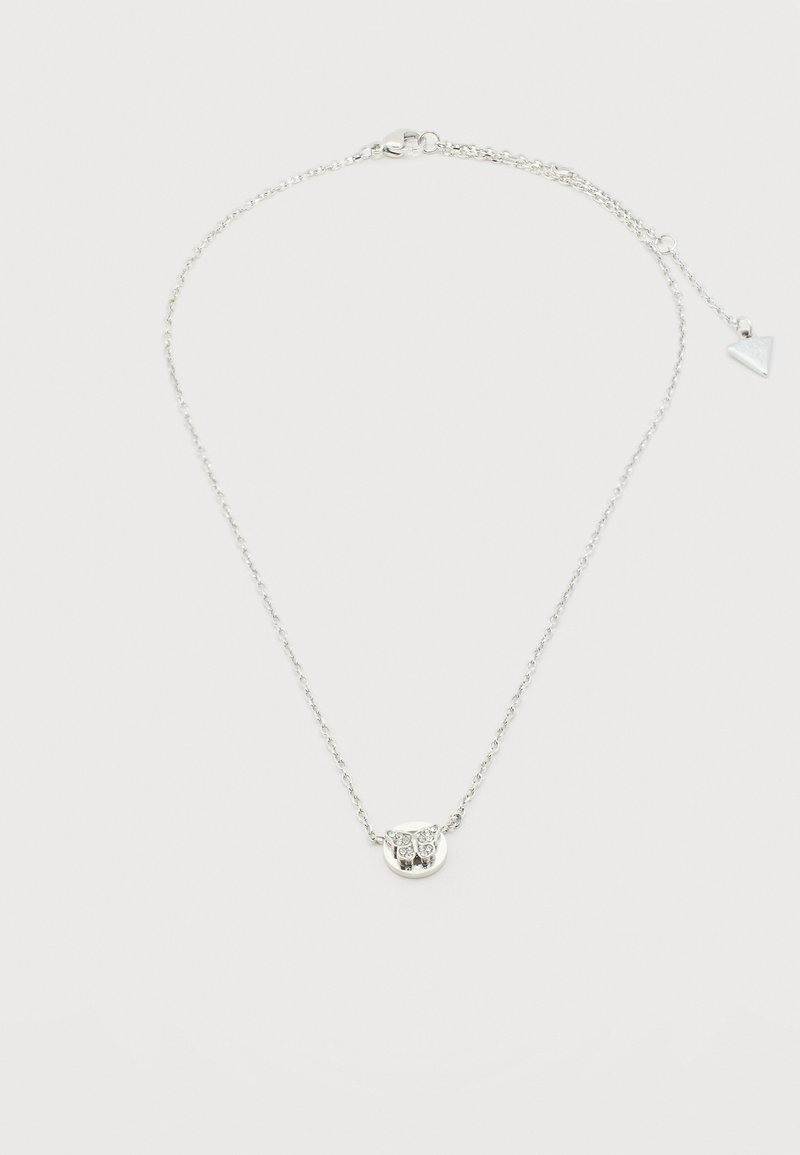 Collier délicat en chaîne argentée avec un petit pendentif rond orné d'un motif gravé de chouette et un fermoir ajustable avec un charme triangulaire.