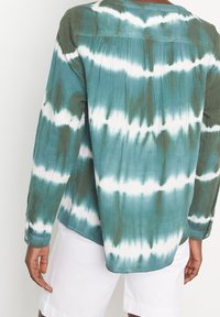 Camicia con bottone in tessuto tie-dye verde e bianco, caratterizzata da maniche lunghe, una vestibilità rilassata e un tessuto testurizzato con un aspetto leggermente stropicciato.