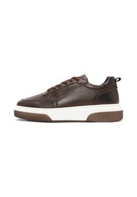 Zapatilla de piel marrón con un acabado texturizado, puntera redonda, cordones marrones, una entresuela blanca y una suela de goma marrón. Cuenta con una cinta de agarre.