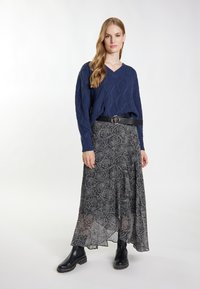 Granatowy sweter z dekoltem w kształcie litery V, wzorzysta czarna długa spódnica, czarny pasek z okrągłą klamrą oraz czarne botki za kostkę.