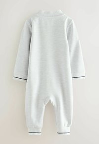 Hellgrauer Jumpsuit mit langen Ärmeln, strukturiertem Stoff, navygestreiften Bündchen und Kragen. Verfügt über einen abgerundeten Rücken und einen Druckknopfverschluss unten.