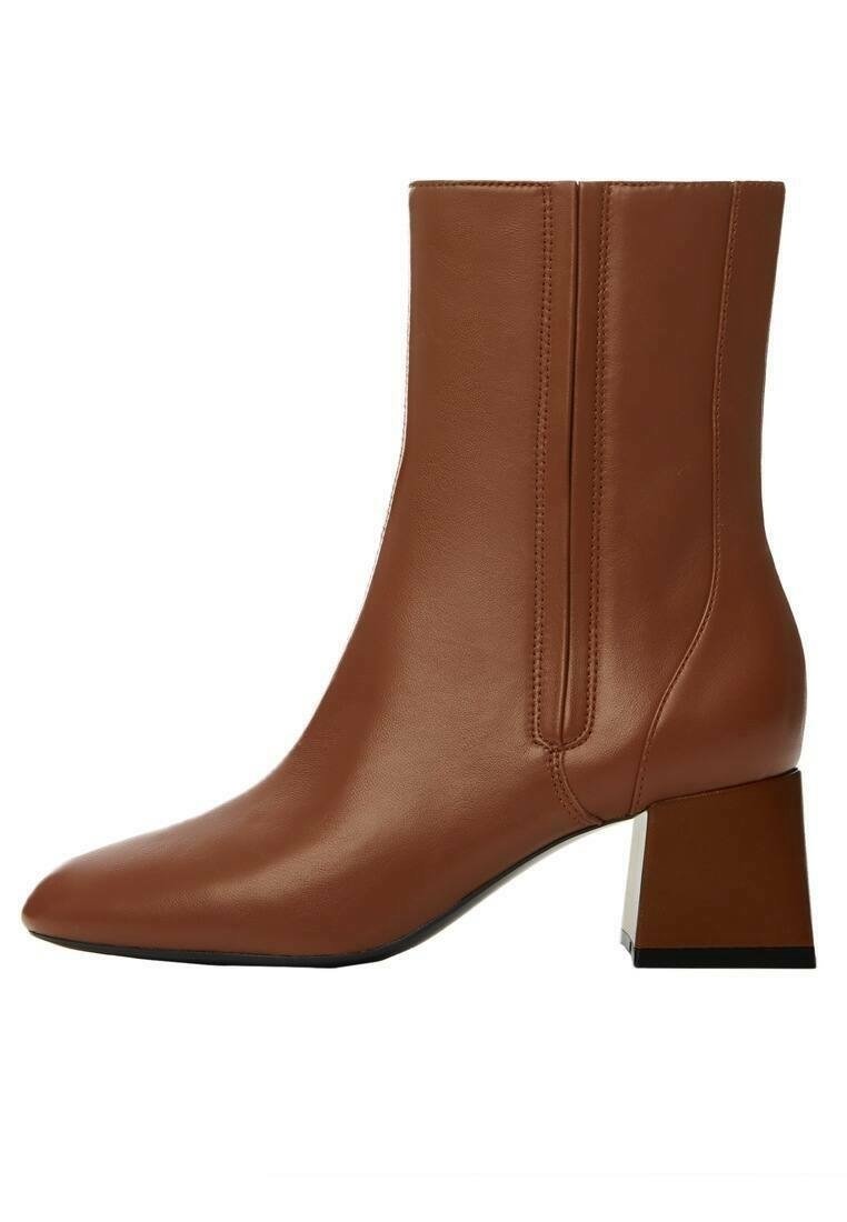 Ruskea nahkainen nilkkuri, jossa on kärjellinen varvas, sivusaumat ja neliömäinen paksu korko. Sileä pinta ja minimalistinen muotoilu.