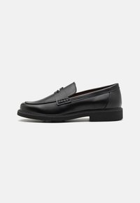 Schwarze synthetische Slipper mit einer markanten gesteppten Vorderseite, gepolstertem Fußbett und flacher Gummisohle; schlankes Design mit minimaler Detailverarbeitung.