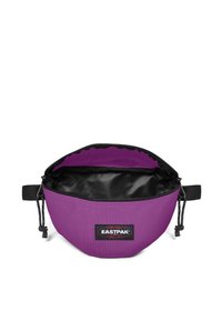 Violetti kangaskassi, jossa on musta sisus, pyöreä muoto, nauhaverhoilun sulku ja Eastpak-logopatchi. Kestävä materiaali, jossa on sileä pinta.