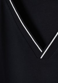 Tissu noir avec un col en V profond bordé de bord-côtes noirs et de fines rayures blanches sur les bords.