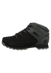 Botas de senderismo negras con acentos sintéticos grises, un collar acolchado y diseño con cordones. Parte superior texturizada con detalle del logotipo en el lateral.