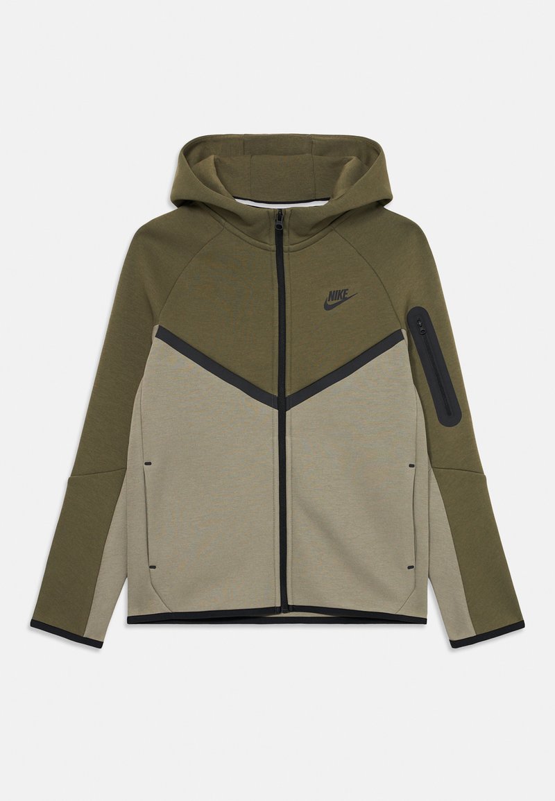 Nike zippes dzseki olíva zöld és bézs színben. Kapucnival, kontrasztos fekete részletekkel és cipzáras zsebbel a bal ujján. Puha anyag.
