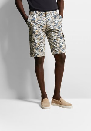 Blumen Cargo-Shorts bestehen aus einem leichten Stoff mit blauen, beigen und braunen Blättern. Sie haben seitliche Taschen und einen Knopfverschluss.