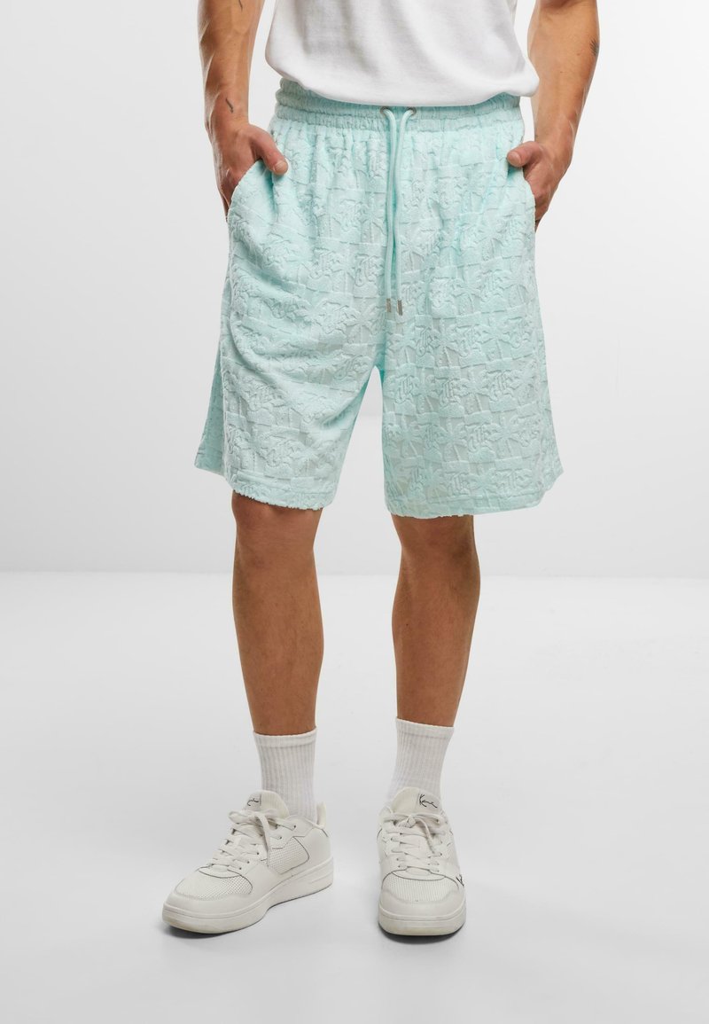 Lysblå teksturerede shorts med en snoretræk i taljen, sidelommer og et mønstret stof. Båret med hvide sneakers og hvide sokker.