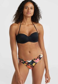 Juodas bandeau tipo bikini viršus su reguliuojamomis petnešomis, derinamas su žemais bikini apatiniais, turinčiais spalvingą gėlių raštą juodame fone.
