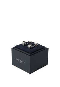 Gemelos de tono plateado con diseño de nudos entrelazados, presentados en una caja cuadrada negra con un inserto azul marino, con el logo "HACKETT" en la parte frontal.