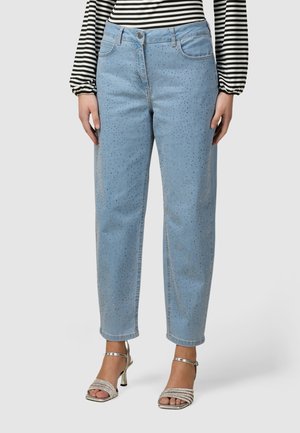 Hellblaue Jeans mit kleinen Strasssteinen, getragen mit silberfarbenen High-Heel-Sandalen und einem schwarz-weißen, langärmligen gestreiften Oberteil.