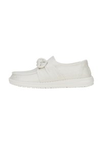 Baskets blanches à enfiler avec un accent noué sur le dessus, fabriquées en tissu texturé, dotées d'une semelle en caoutchouc flexible.