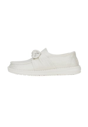 White slip-on shoes with a knotted accent on the upper, made from textured fabric, featuring a flexible rubber sole.