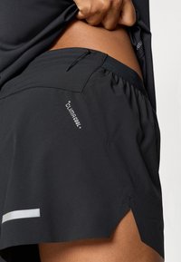 Zwarte hardloopshorts gemaakt van een lichtgewicht, ademende stof. Voorzien van een reflecterende streep, een elastische tailleband en een gesplitste zoom.