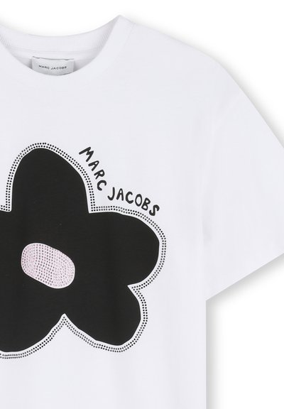 Hvid T-shirt med et stort sort blomstergrafik med en lyserød midte. Mærket "MARC JACOBS" er trykt over i sort. Blødt bomuldsmateriale.
