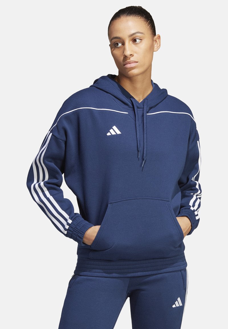 Marineblaue Kapuzenjacke mit weißen Streifen entlang der Ärmel und Schulter, Kängurutasche und Kordelzugkapuze, aus weichem Stoff.